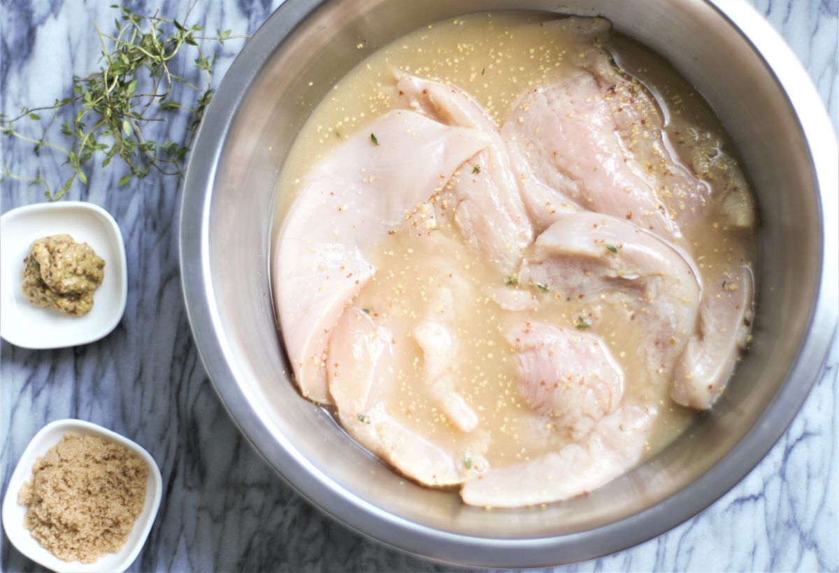 A bowl with marinating chicken breast.