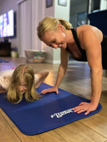 Woman working out in living room with daughter