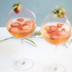 2 wine glasses filled with rosa wine, strawberries and tangerines