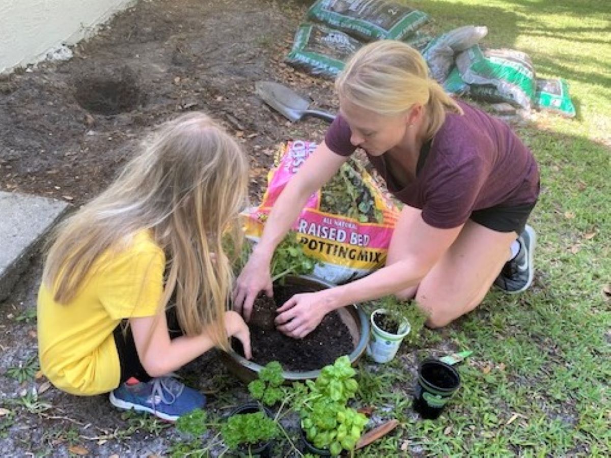 a woman and child planting a herb garden