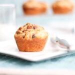 raisin muffin on a plat with knife and butter and a glass of milk