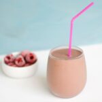 a glass with a raspberry and chocolate protein shake.