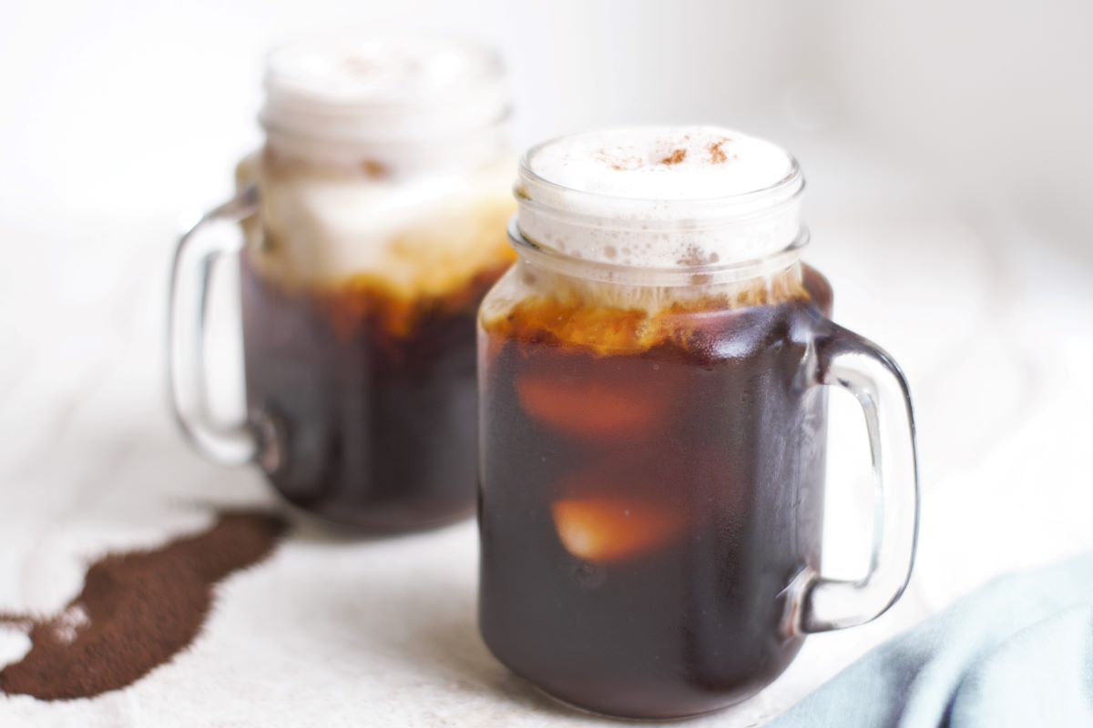 Two mugs of cold brew with cinnamon almond milk foam.