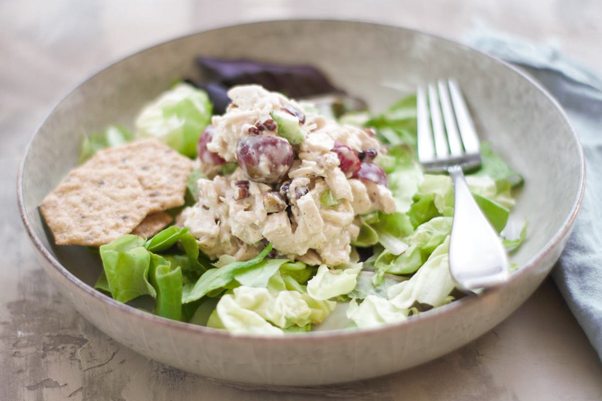A bowl with lettuce and chicken salad. 