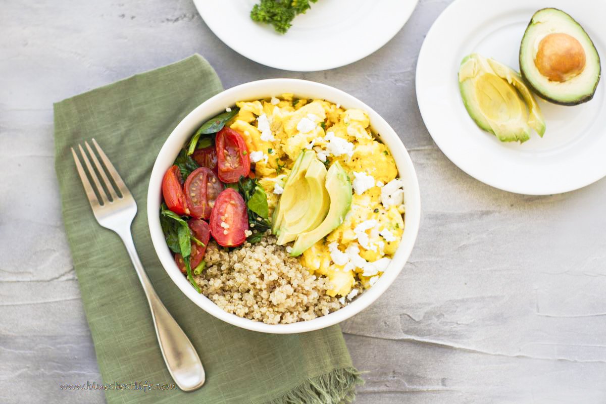 a breakfast bowl with quinoa, eggs, sauteed veggies and avocado