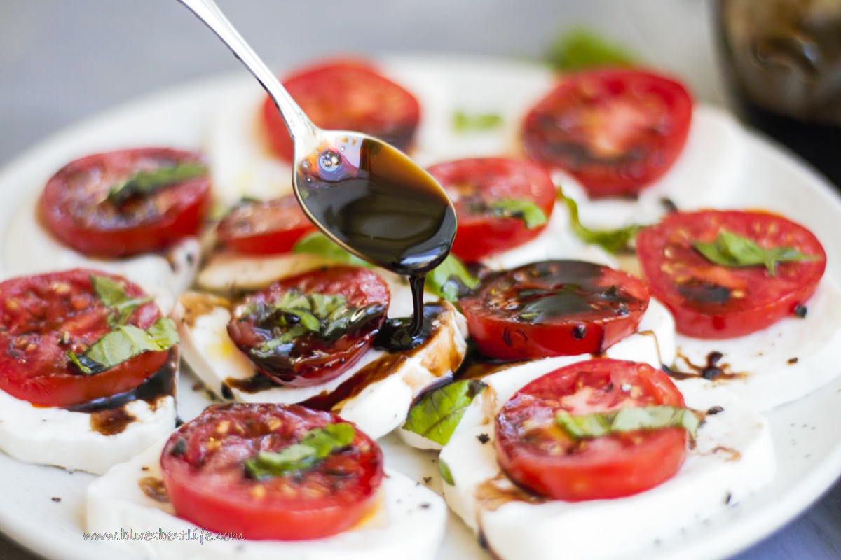 caprese salad with balsamic glaze being drizzled over the top