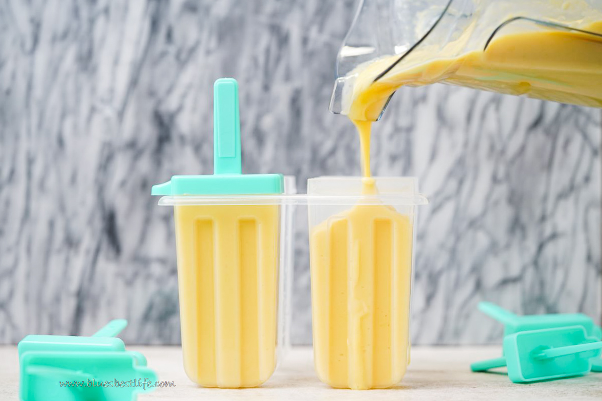 pouring the blended mango into the popsicle molds