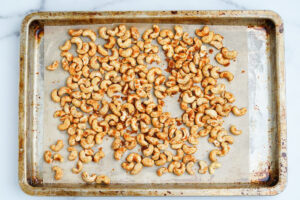 raw cashews with spices ready to roast in the oven on baking sheet