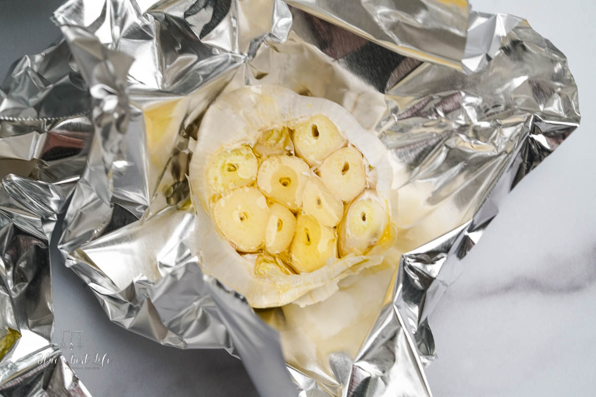 Drizzling the garlic with olive oil and wrapping in foil