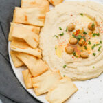 Hummus spread on a plate with pita chips