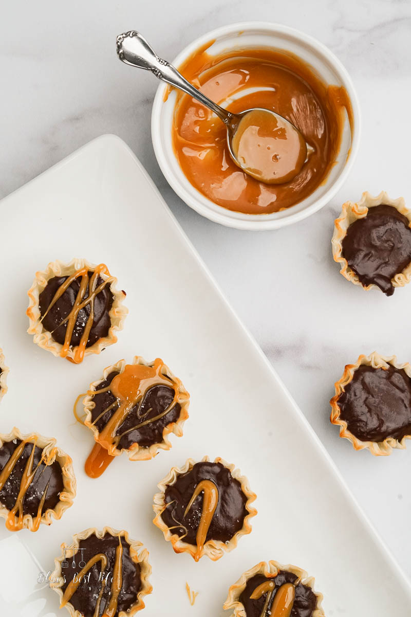 mini chocolate tarts on serving plate with caramel sauce