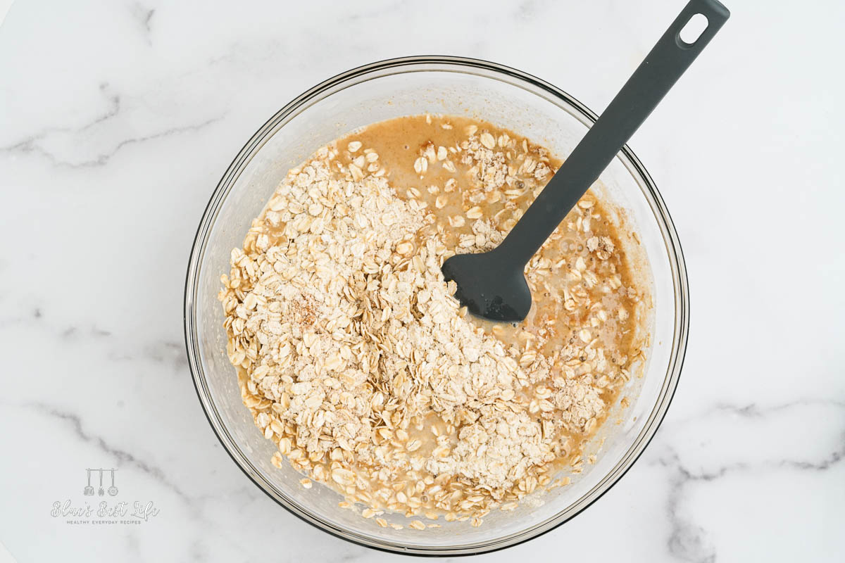 A mixing bowl with the wet ingredients stirred into the oats.