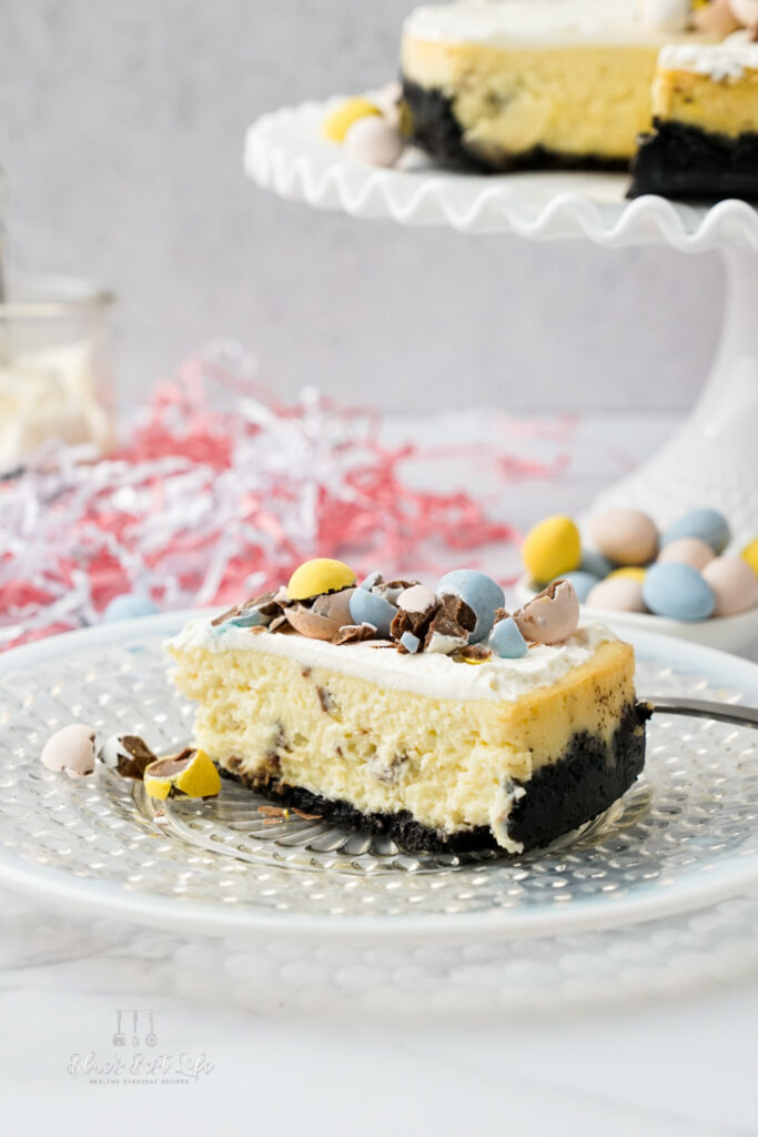 A mini egg cheesecake slice and the cake on a cake stand.