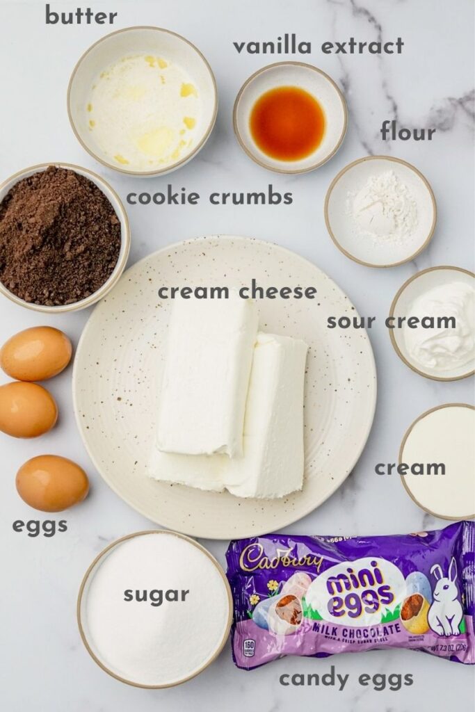 ingredients for mini egg cheessecake: cream cheese, cookie crumbs, cream, sour cream, eggs, sugar, vanilla extract, butter, and Cadbury candies.