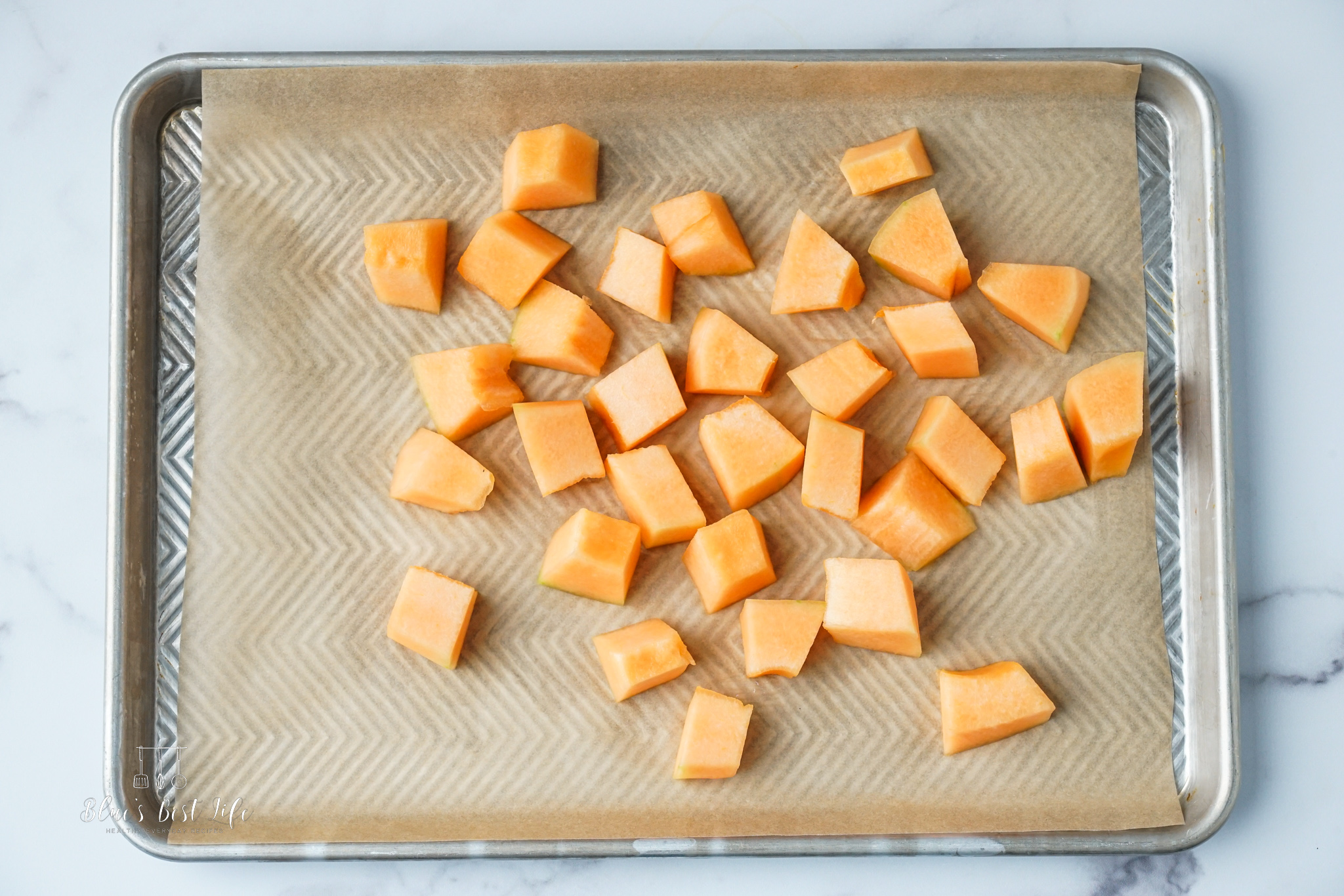 The cantaloupe chunks on a parchment lined baking sheet.  