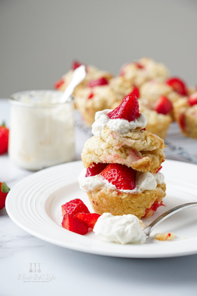 A shortcake muffin with whipped cream and berries.  