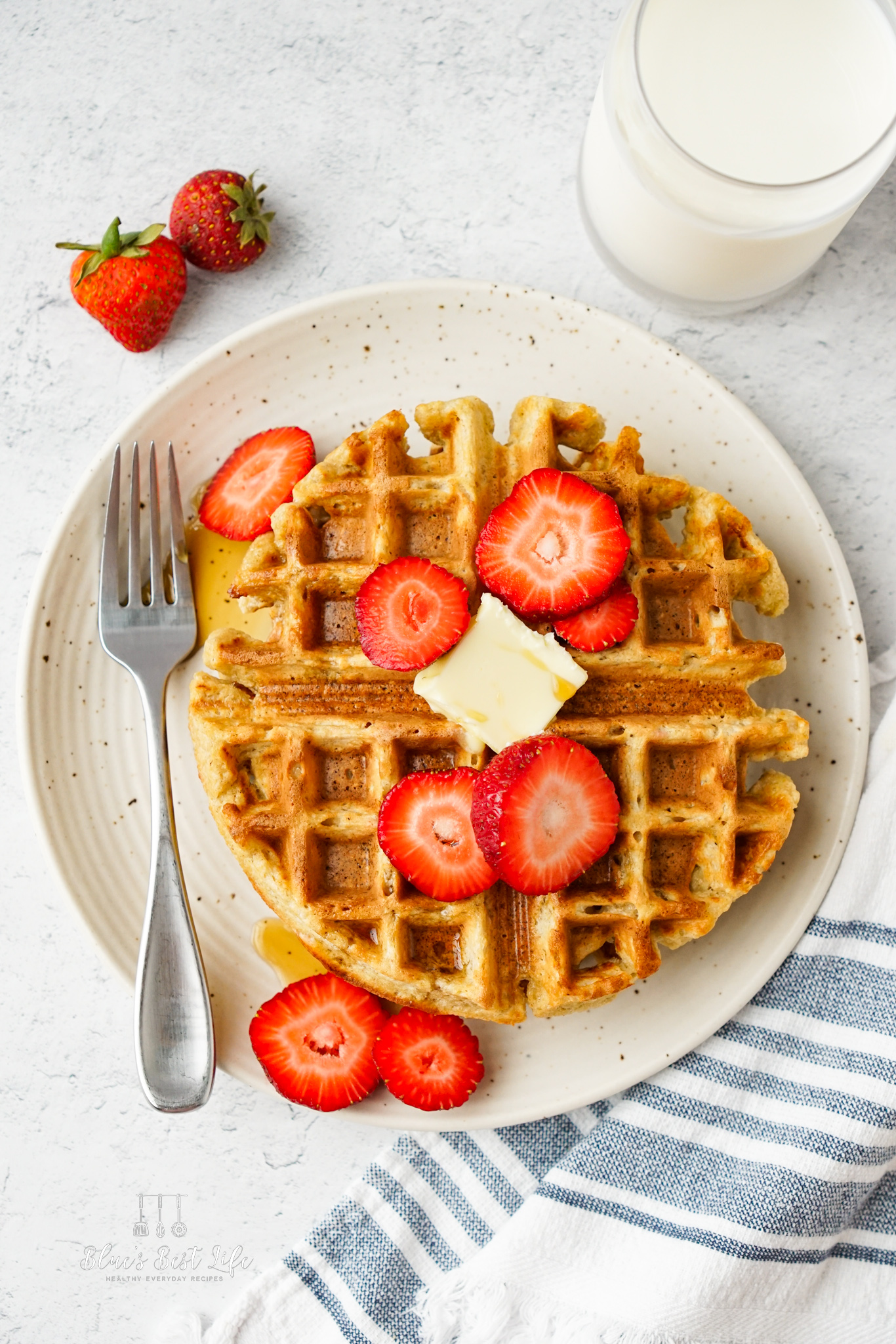 The waffles with strawberries, butter and syrup.
