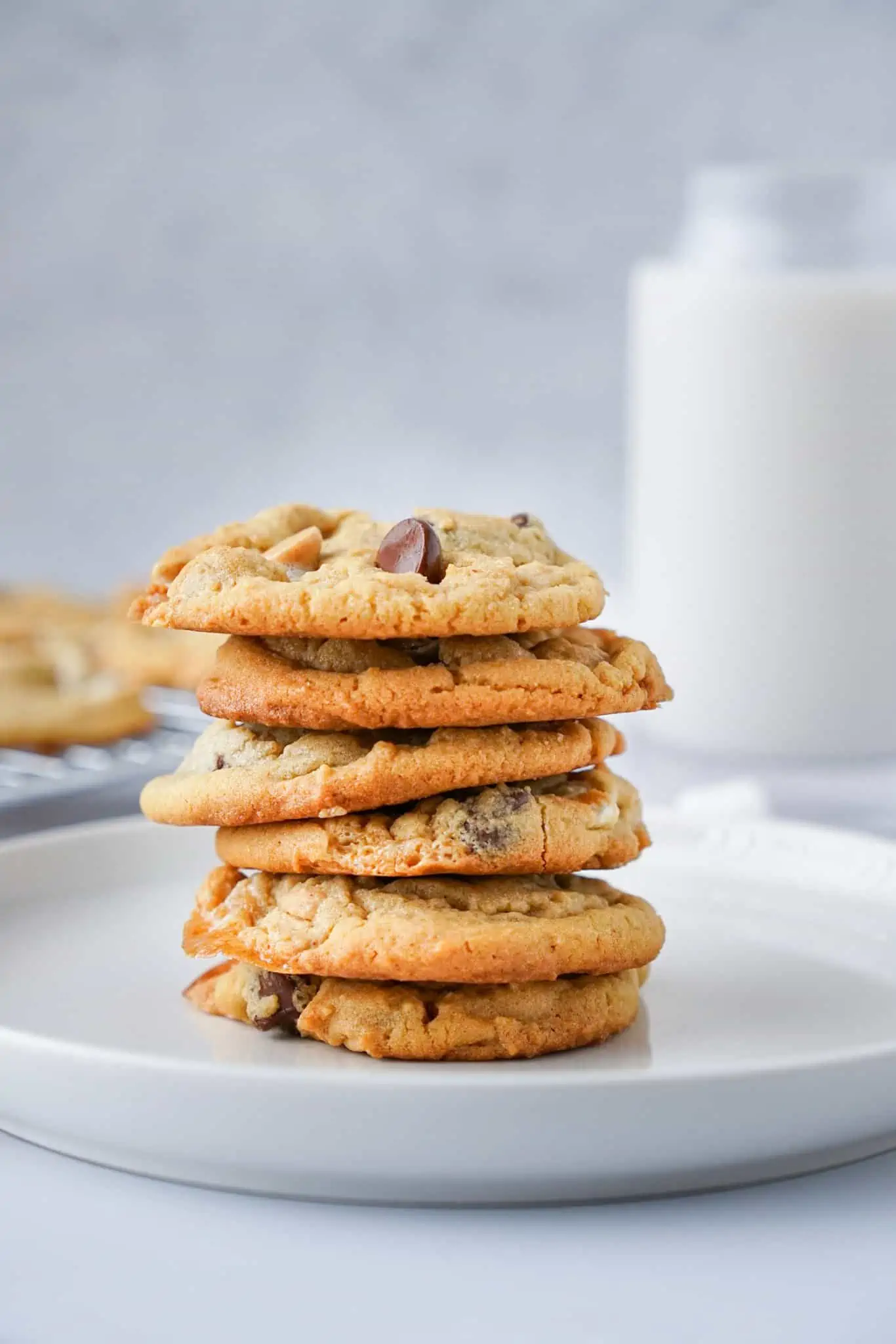 A stack of peanut butter chocolate chip cookies with a glass of milk.