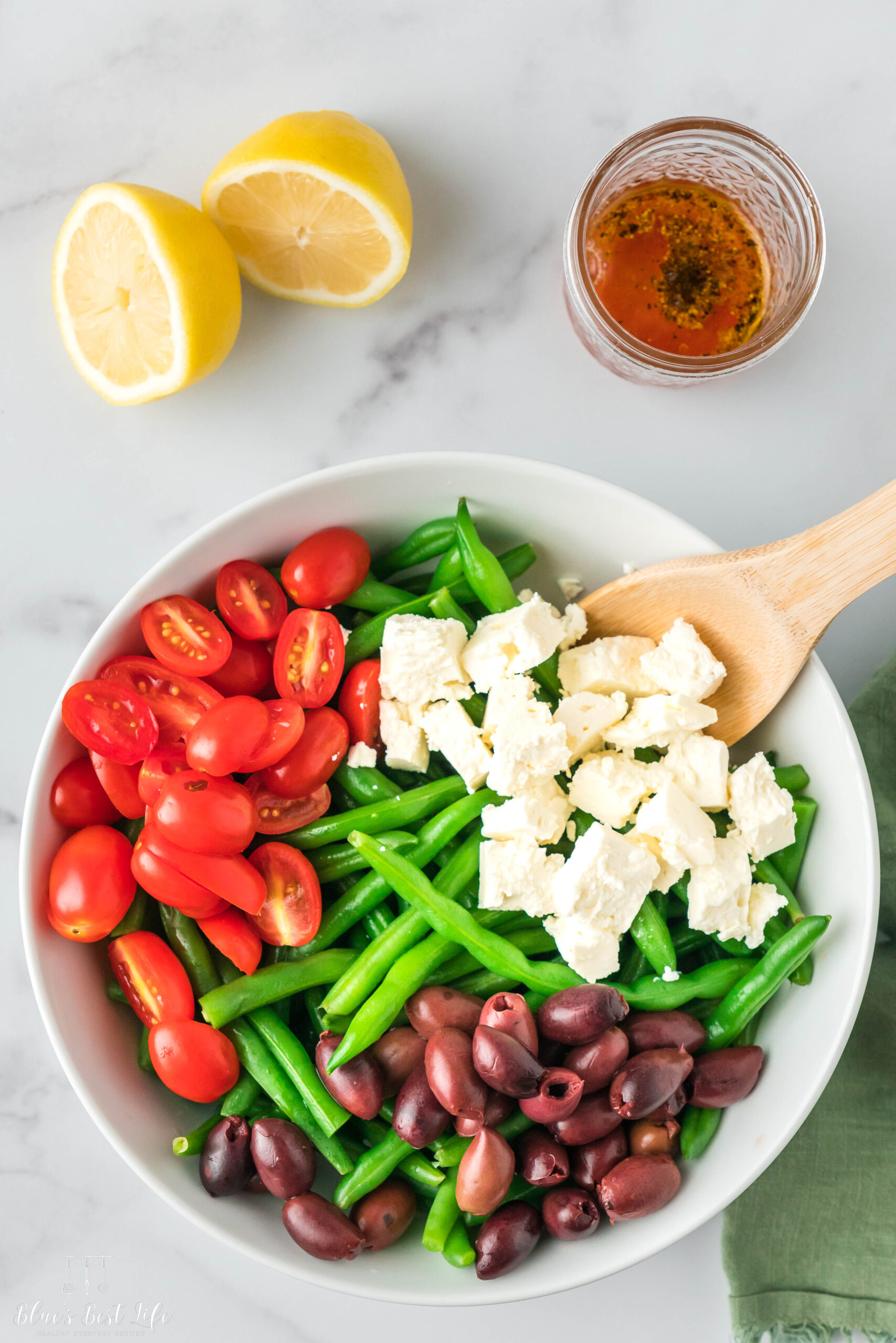 The green beans, tomatoes, olives and feta cheese in a bowl.