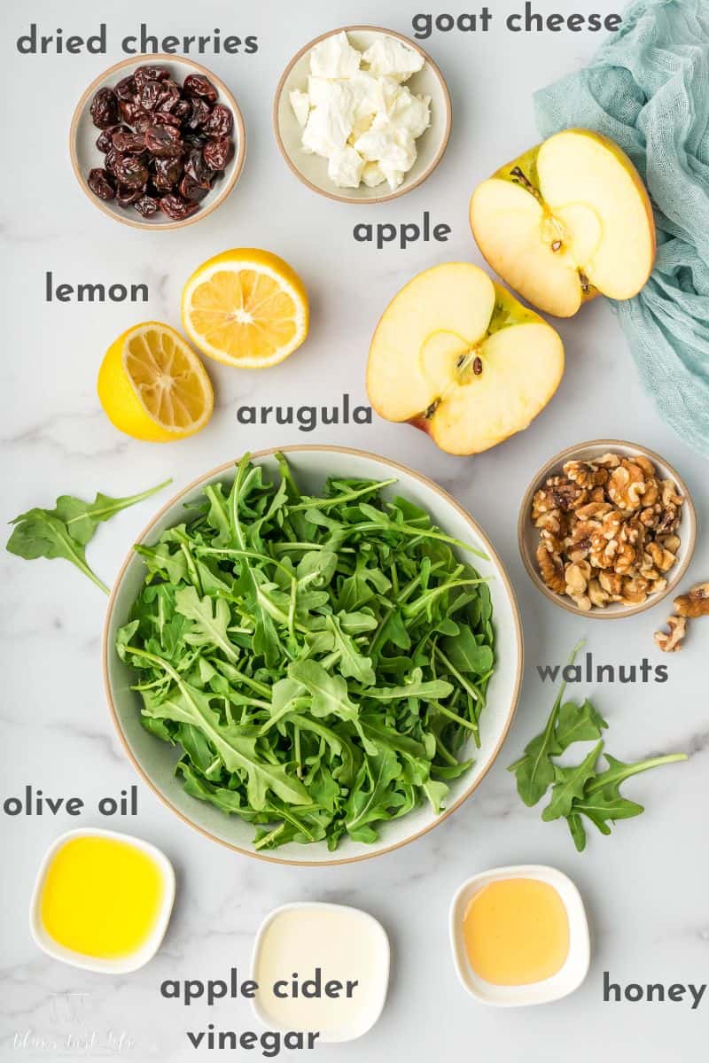 arugula salad ingredients: dried cherries, goat cheese, lemon, apple, arugula, walnuts, olive oil, apple cider vinegar & honey.