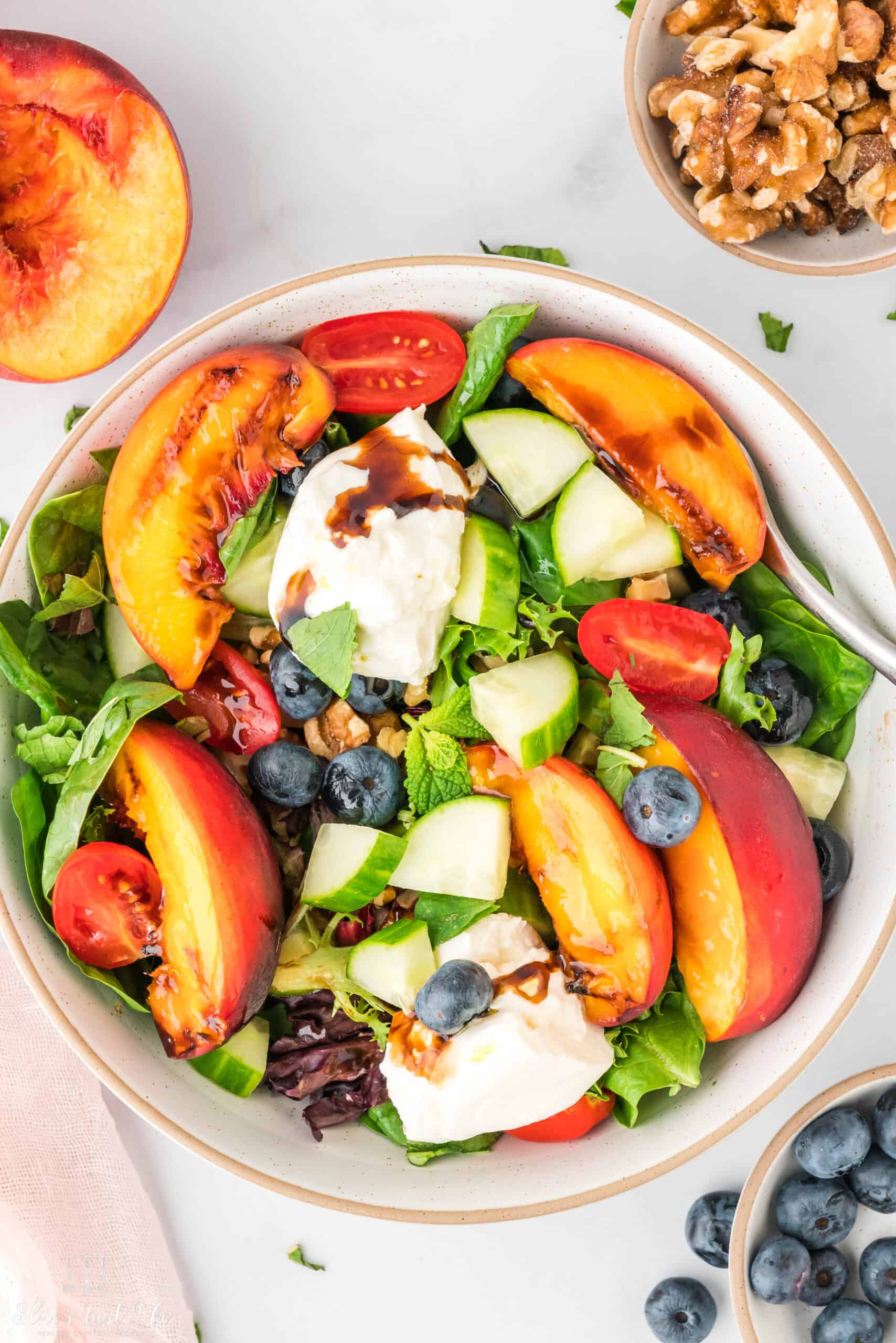 A close up of the serving bowl with the peach and burrata salad.