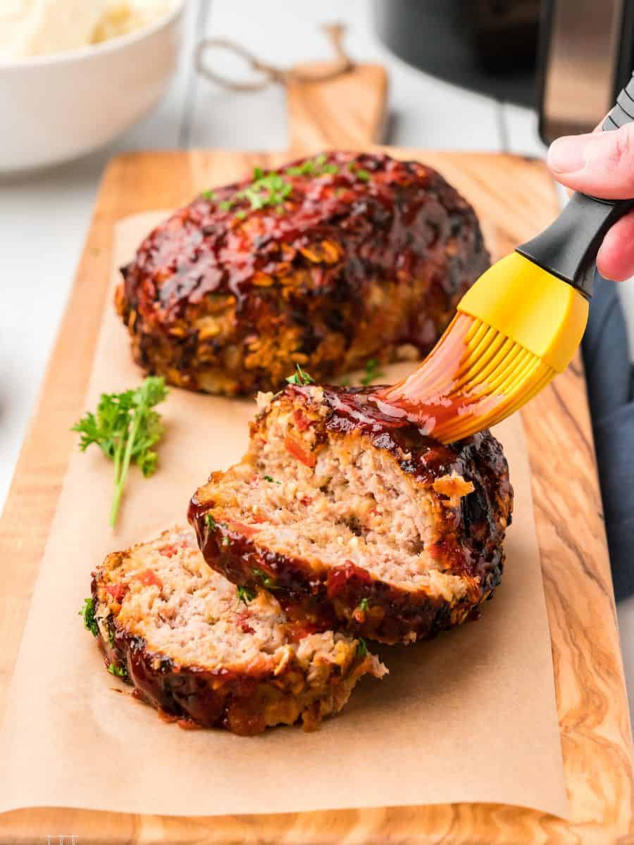 Brushing the meatloaf with glaze. 