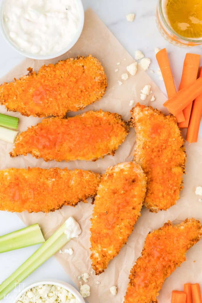 A table top shot of Spicy Air Fryer Buffalo Chicken Tenders with celeries, carrots, and dips