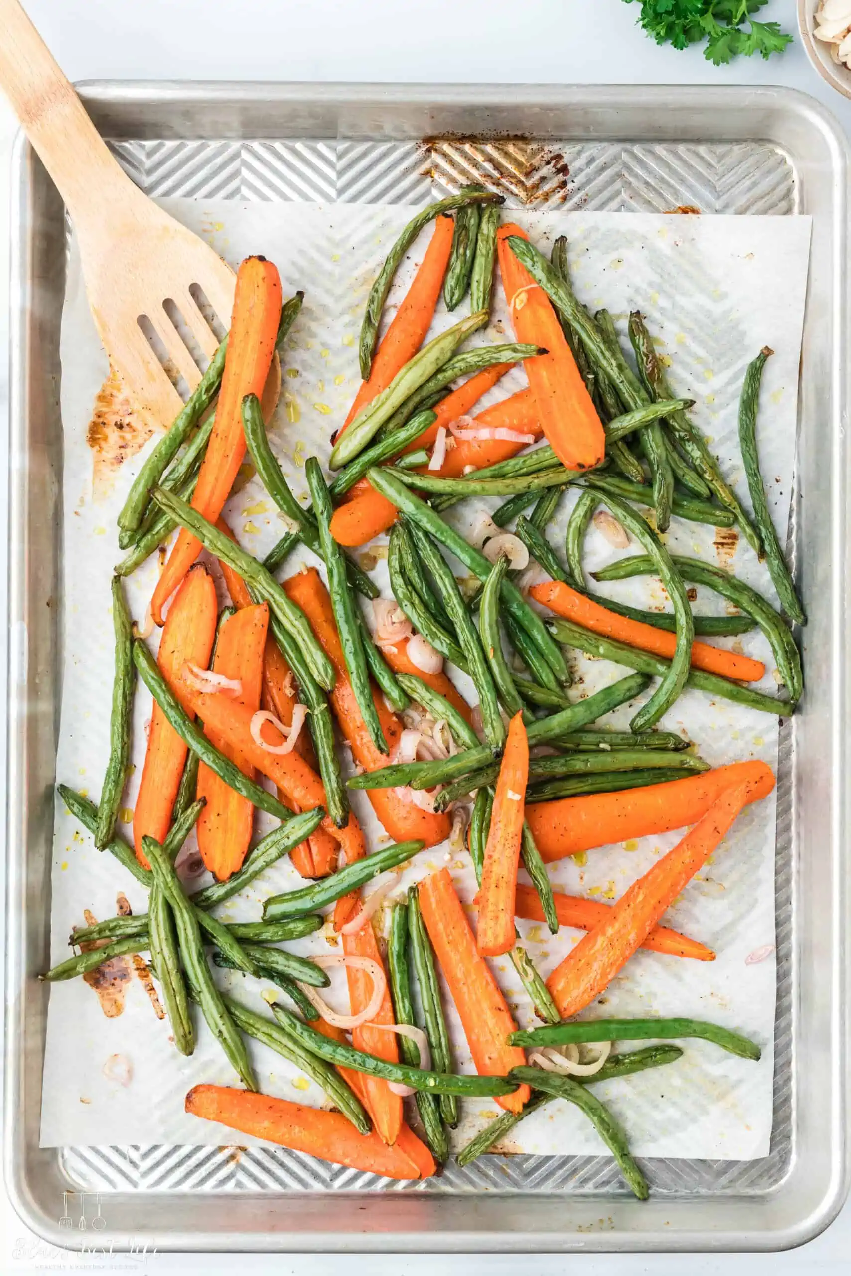 Roasted carrots and green beans on a baking tray.
