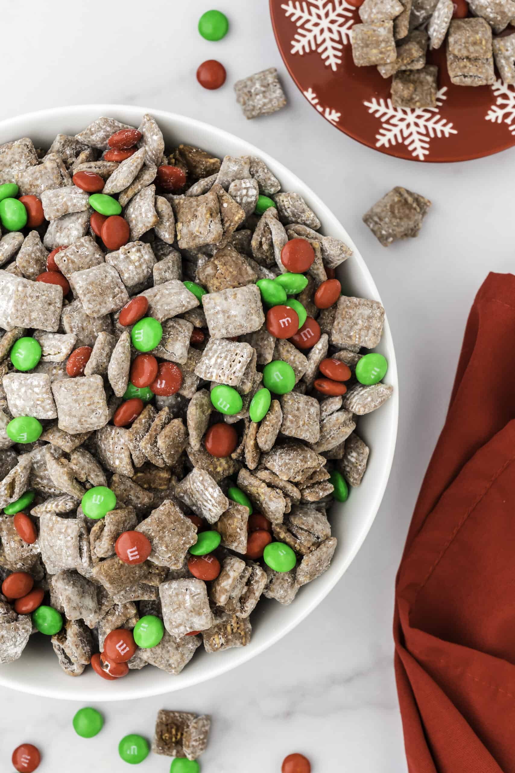 A bowl of muddy buddies with green and red M&M's.