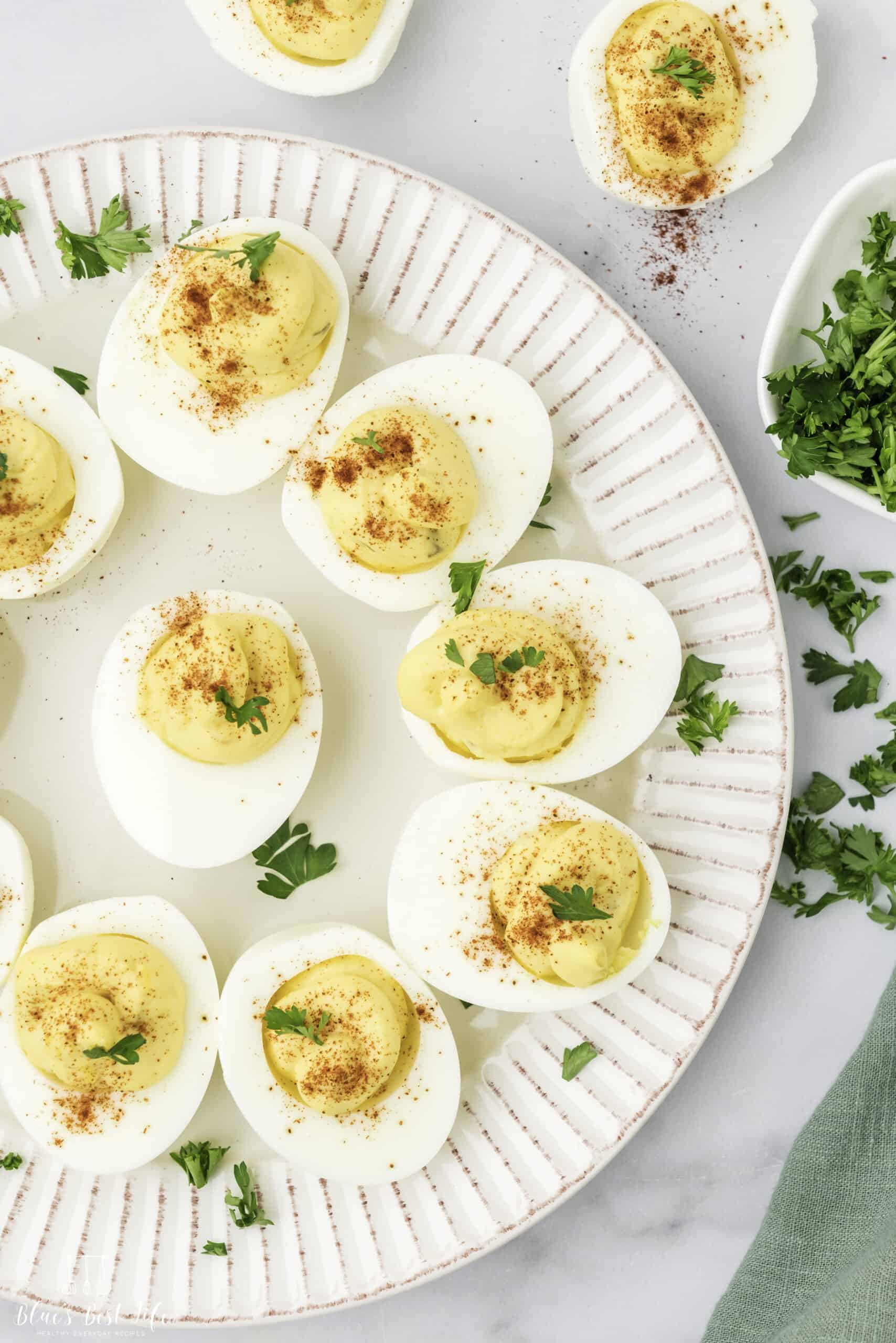 A plate with deviled eggs garnished with paprika and parsley.