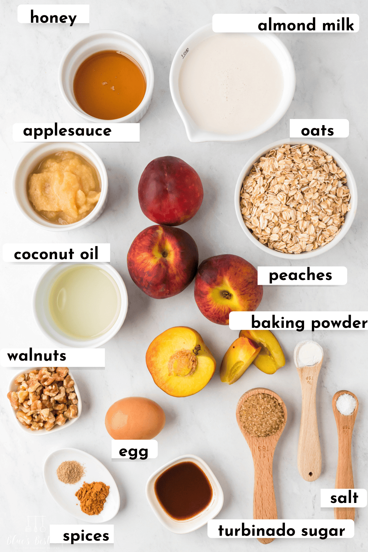 The ingredients to make peach baked oatmeal: honey, almond milk, applesauce, oats, coconut oil, peaches, baking powder, walnuts, egg, spices, turbinado sugar, & salt. 