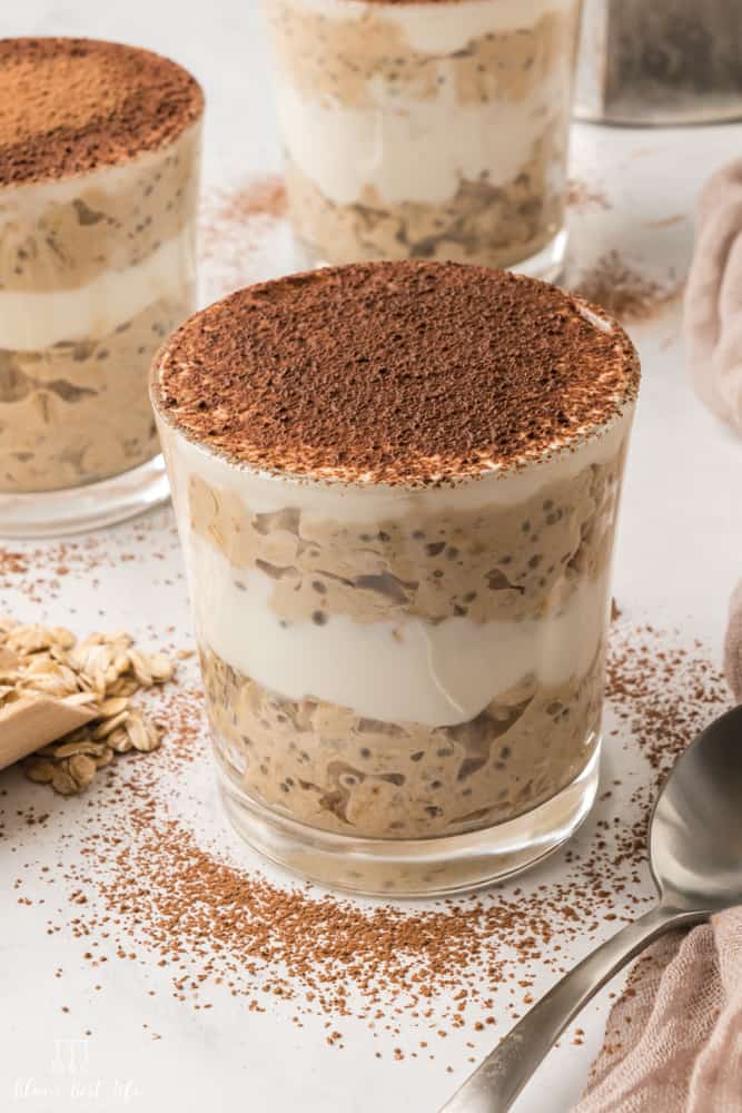 A close up of the overnight oats sprinkled with cocoa powder. Other two servings can be seen on the sides. 