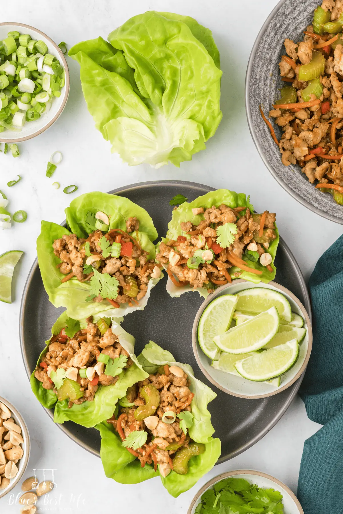 Chicken lettuce wraps on a plate with lime wedges. 