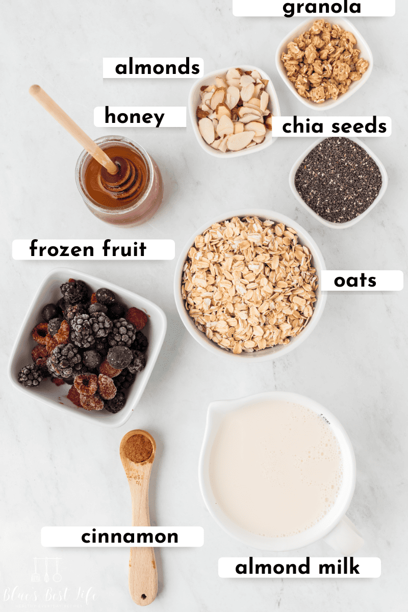 Ingredients needed for overnight oats with frozen fruit: granola, almonds, honey, chia seeds, a bowl of frozen fruits. oats, cinnamon, & almond milk.
