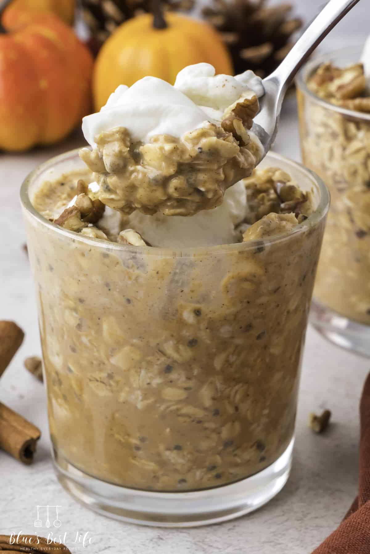 A glass of pumpkin pie overnight oats with a spoonful of  overnight oats. 