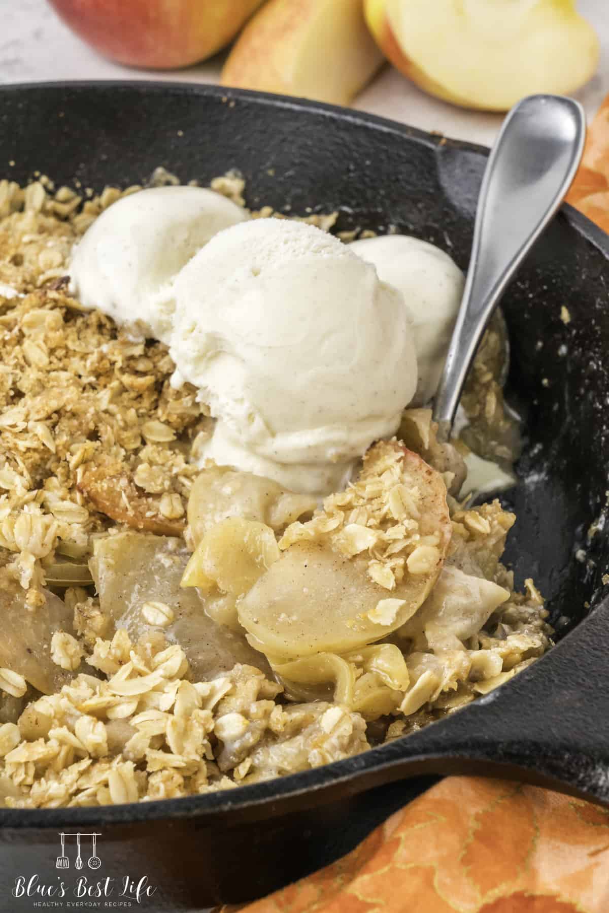The apple crisp in a cast iron skillet with ice cream. 