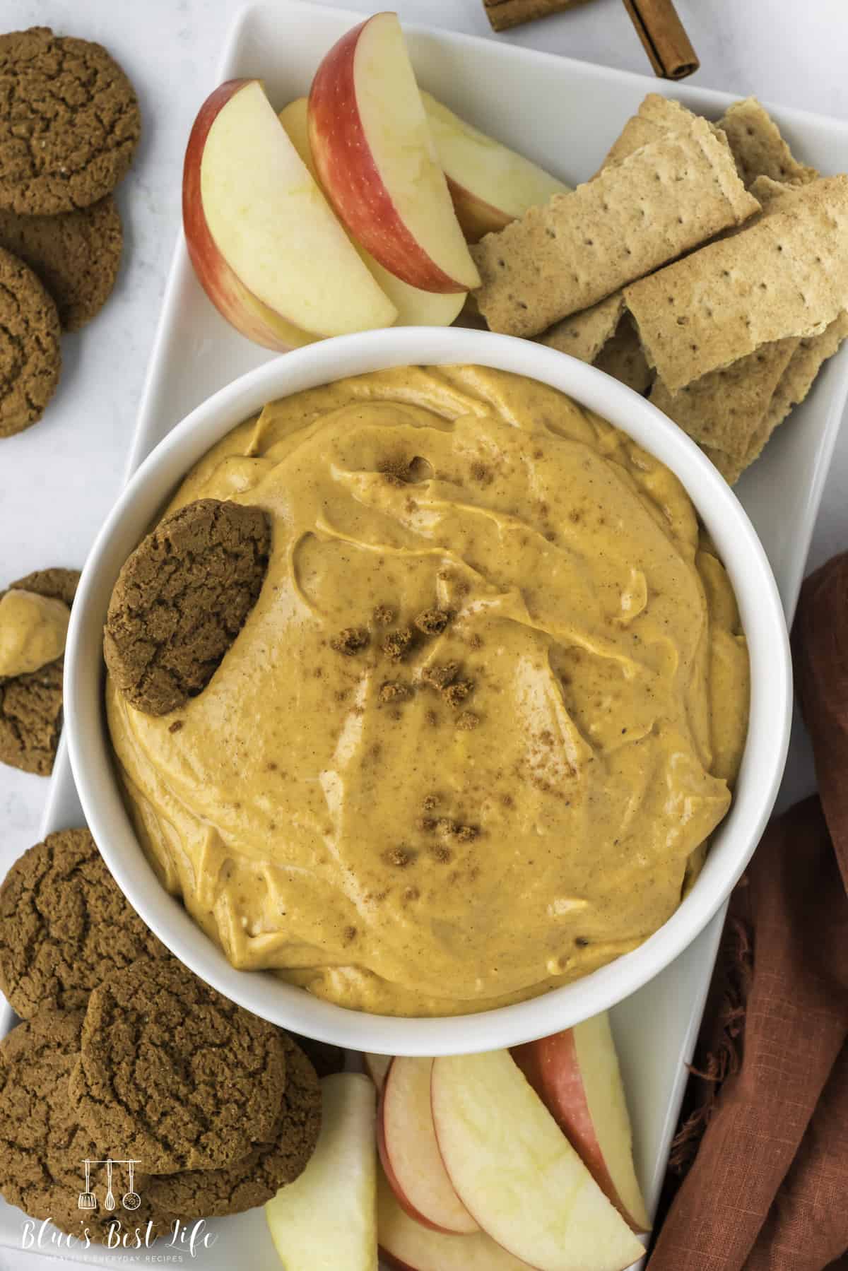 A bowl with pumpkin dip and gingersnap cookies. 