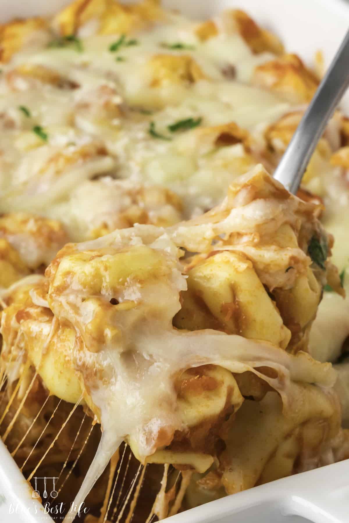 A close-up shot of the tortellini pasta casserole, a cheese pull visible from a spoonful of it. 