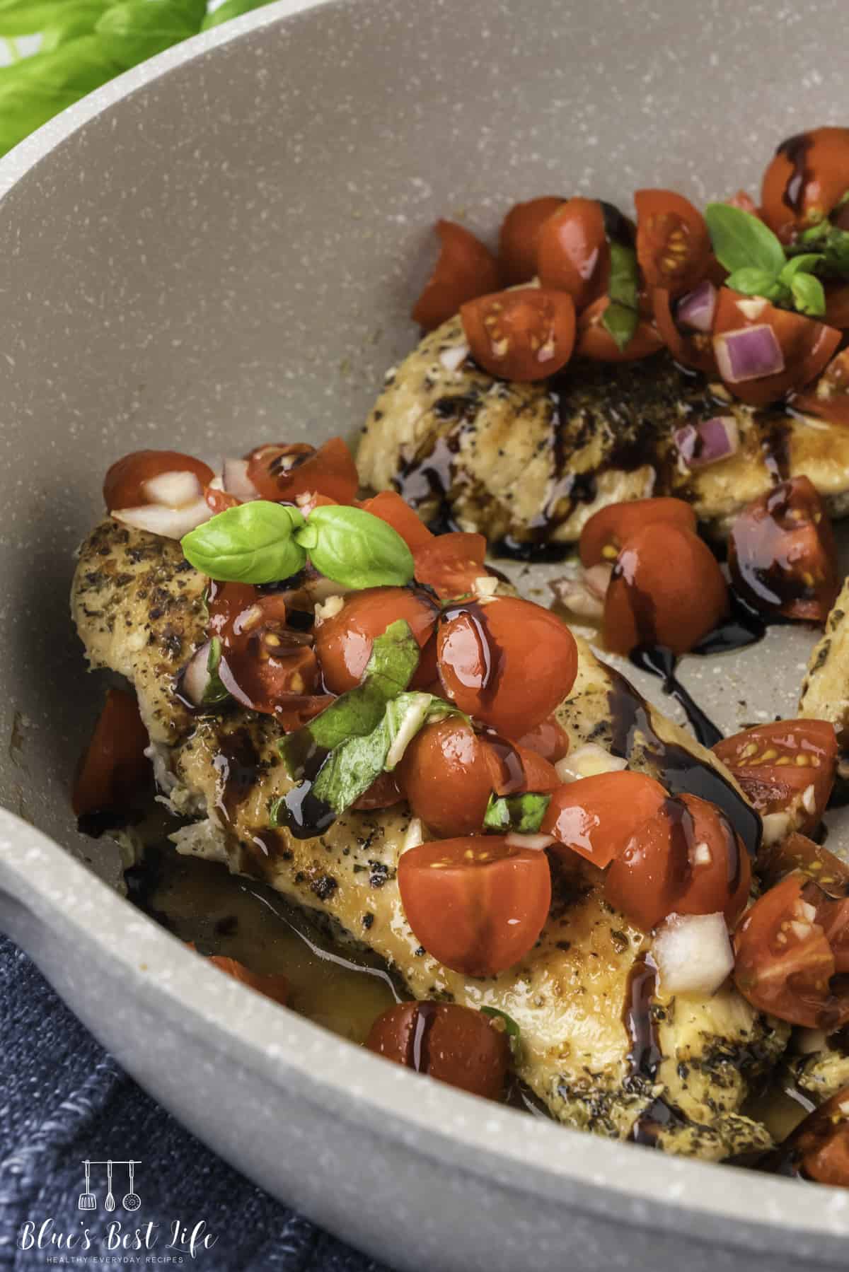 A close up of the chicken with bruschetta topping in the skillet. 