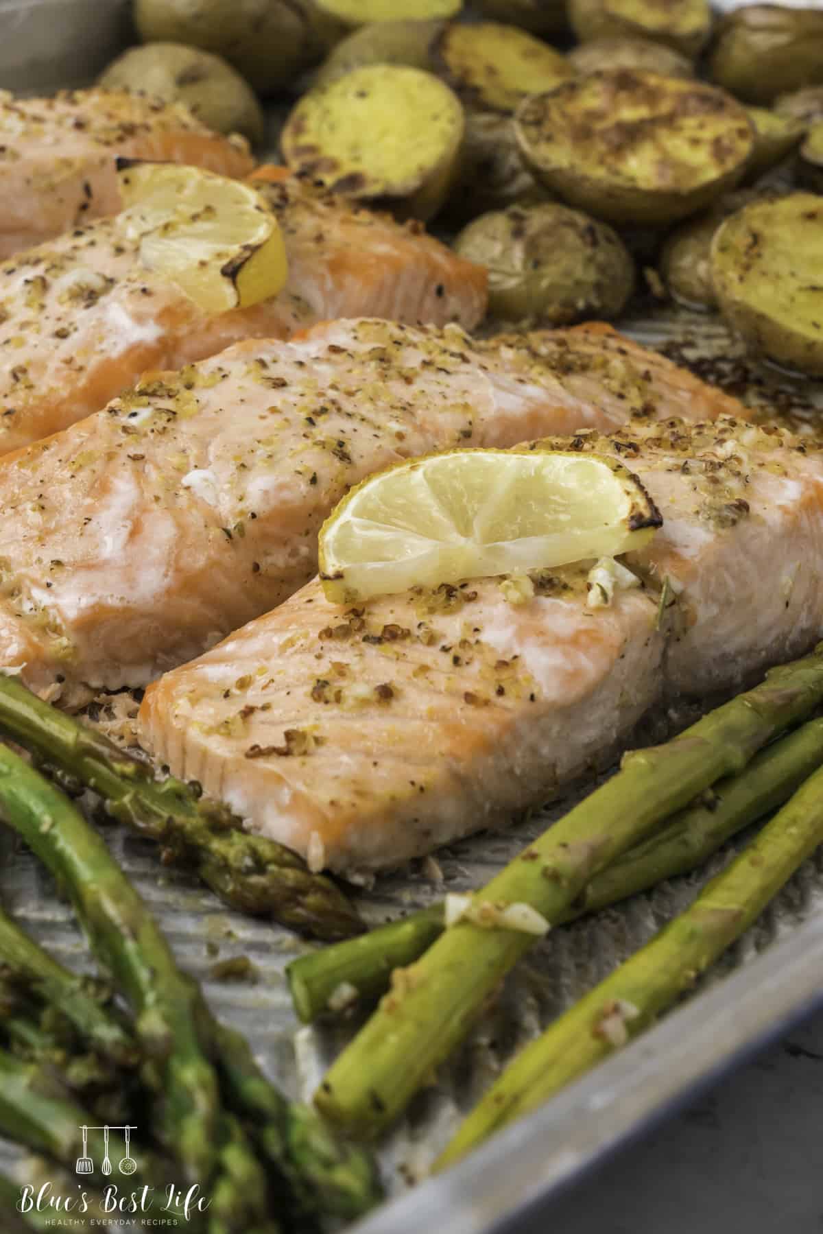 A close-up shot of Salmon With Asparagus with potatoes and asparagus on the side.