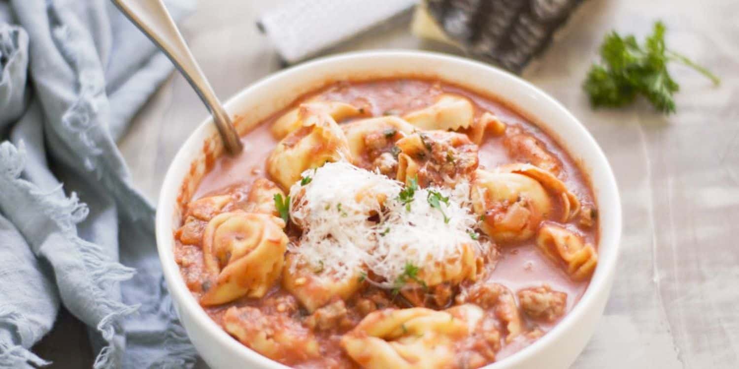 A bowl of Tortellini Soup with a spoon. 