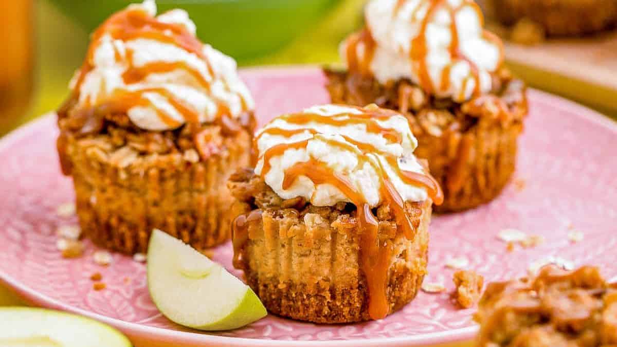 three mini apple cheesecakes with frosting and caramel drizzle