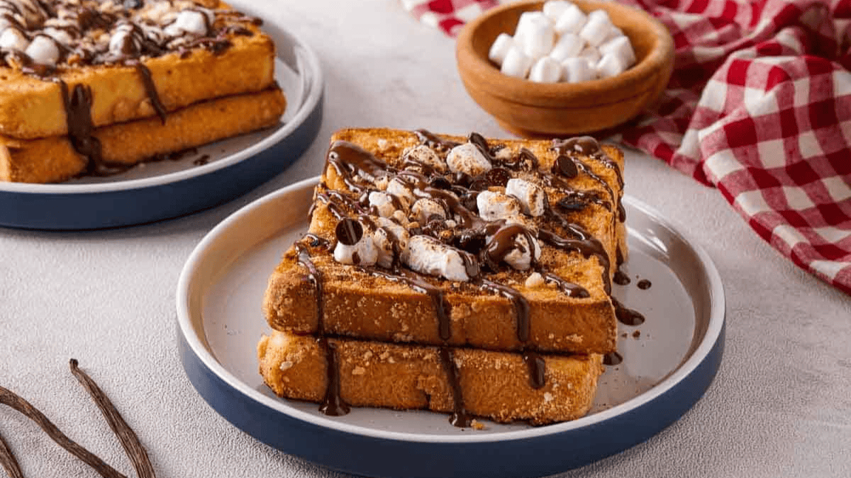 two stacked french toasts topped with chocolate drizzle and torched marshmallows