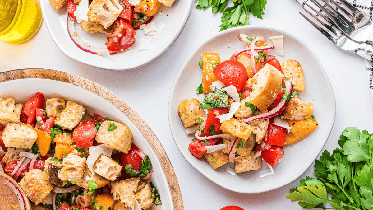 salad on a plate in a big bowl with croutons, red onion, herbs, tomatoes, cheese