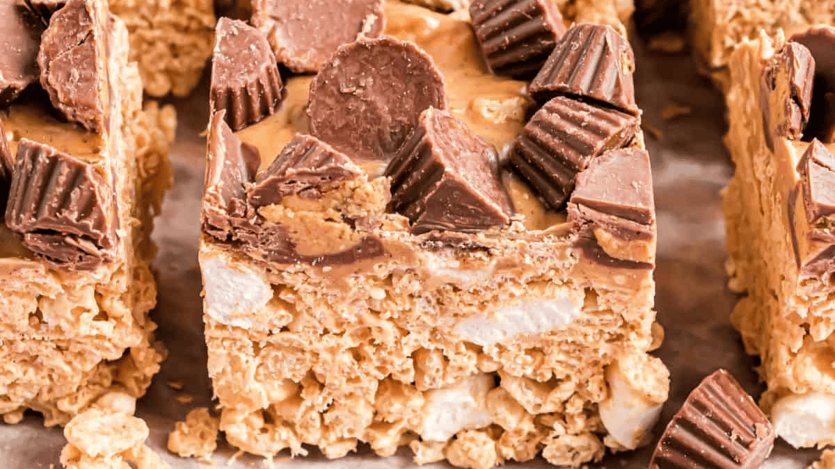 Rice Krispie Treats squares topped  with peanut butter, peanut butter cups, and morcels