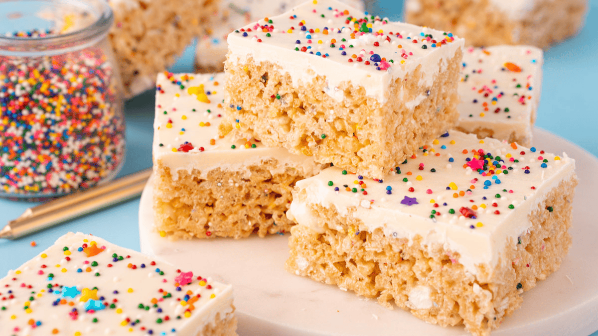 Rice Krispie Treats squares topped with cake frosting and birthday sprinkles