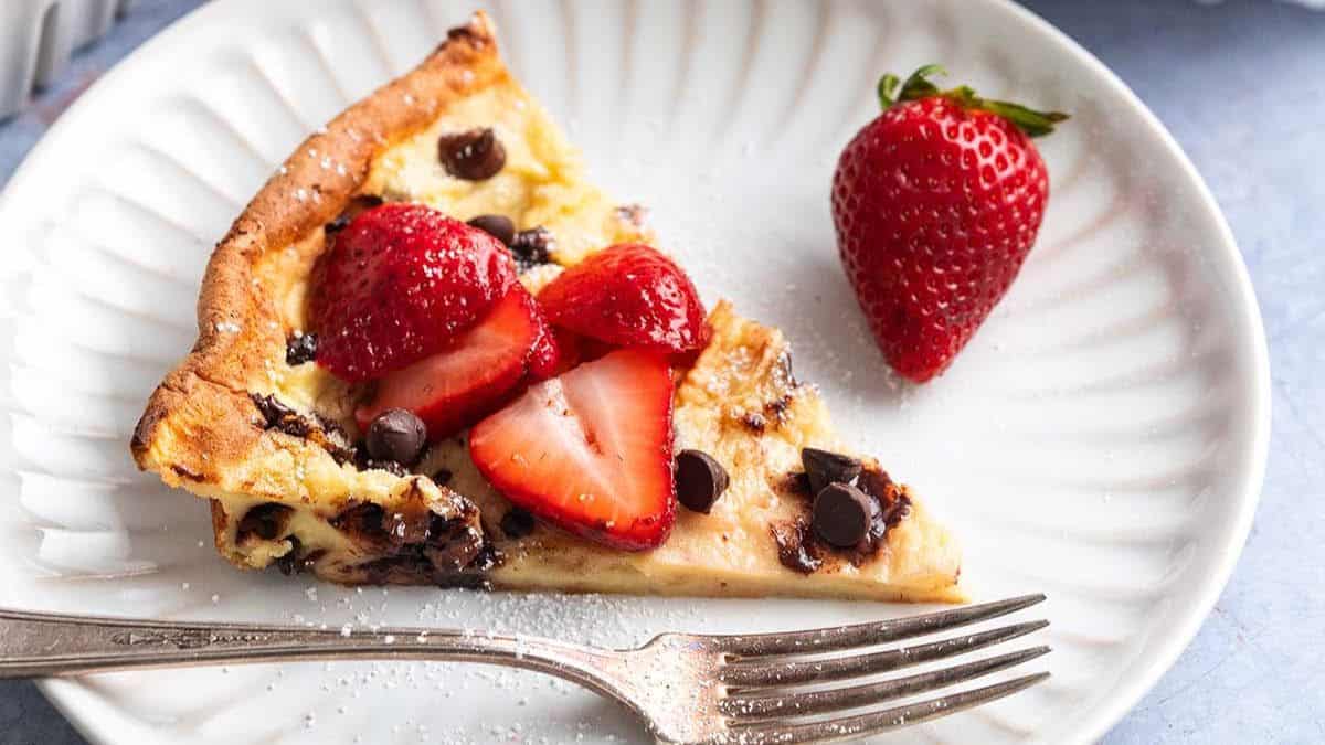 a slice of chocolate chip dutch baby topped with fresh strawberries