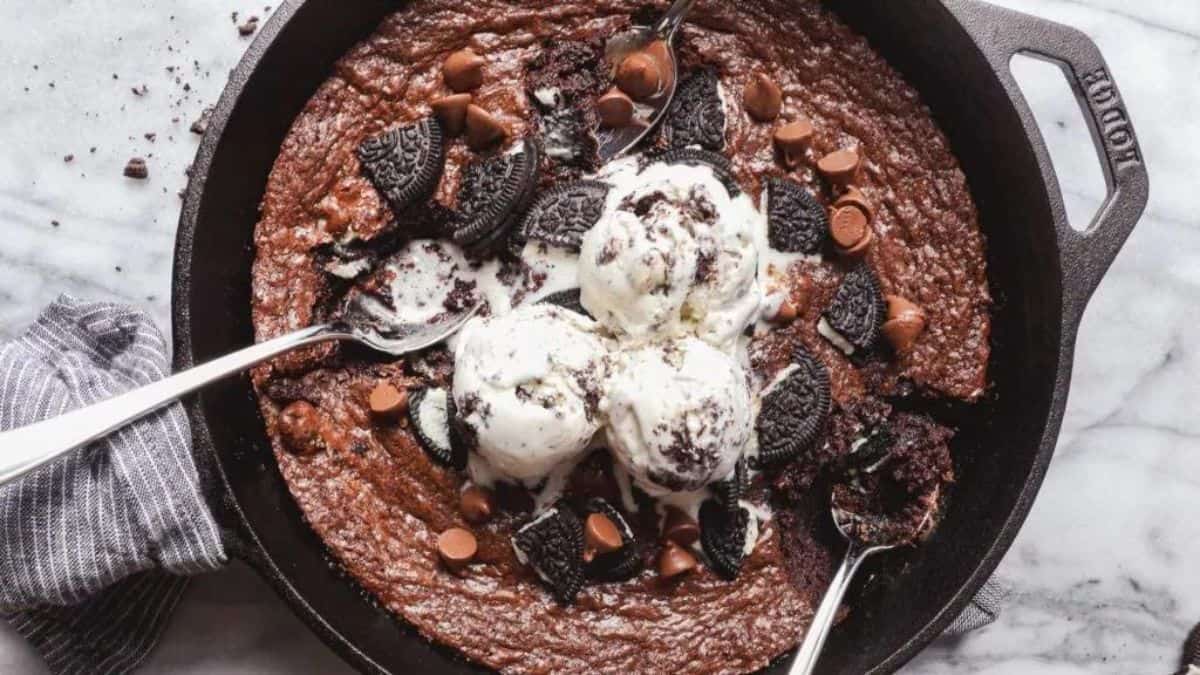 a skillet with chocolate cookie with chocolate chips, crushed Oreo sandwich cookies and vanilla ice cream