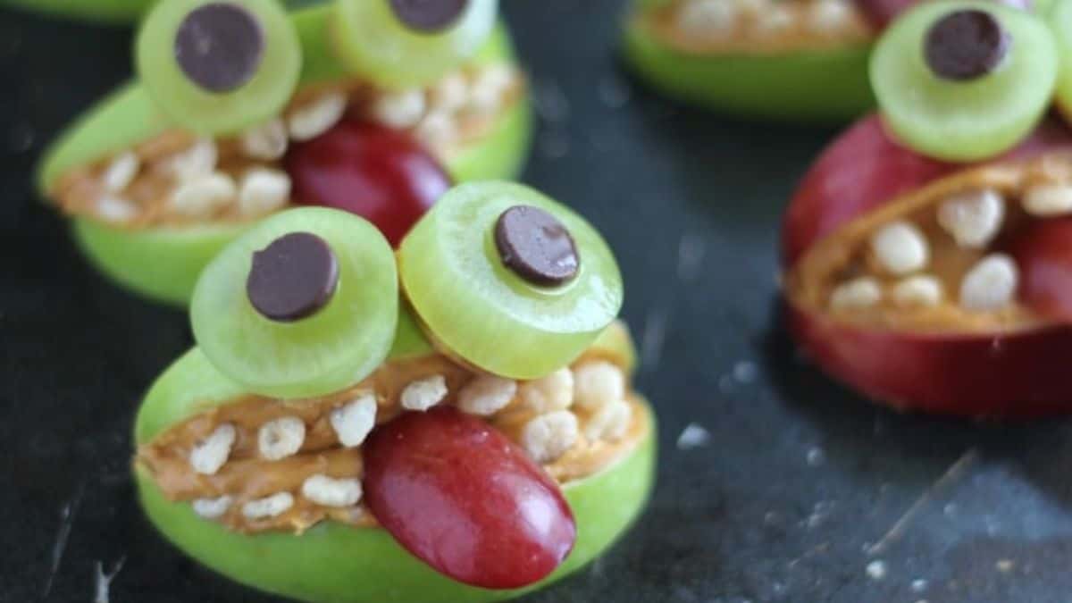 a grape cut horizontally to create a mouth with red grape tongue and green grape slices as eyes