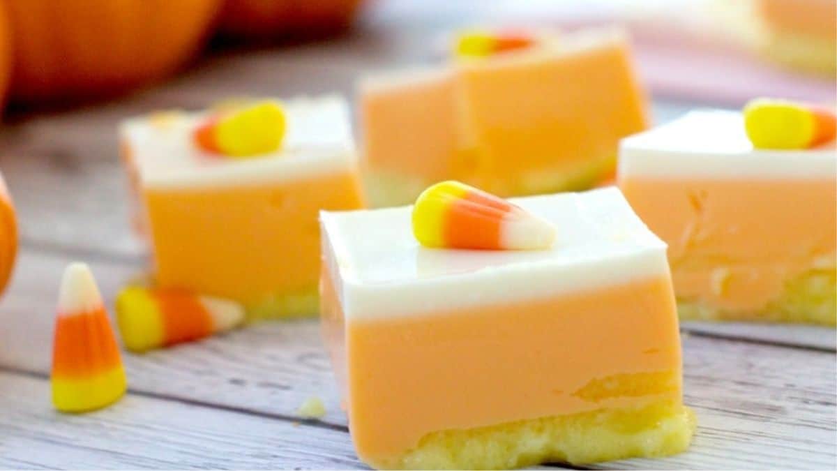 cut square of jello layered dessert with three layers and candy corn on top